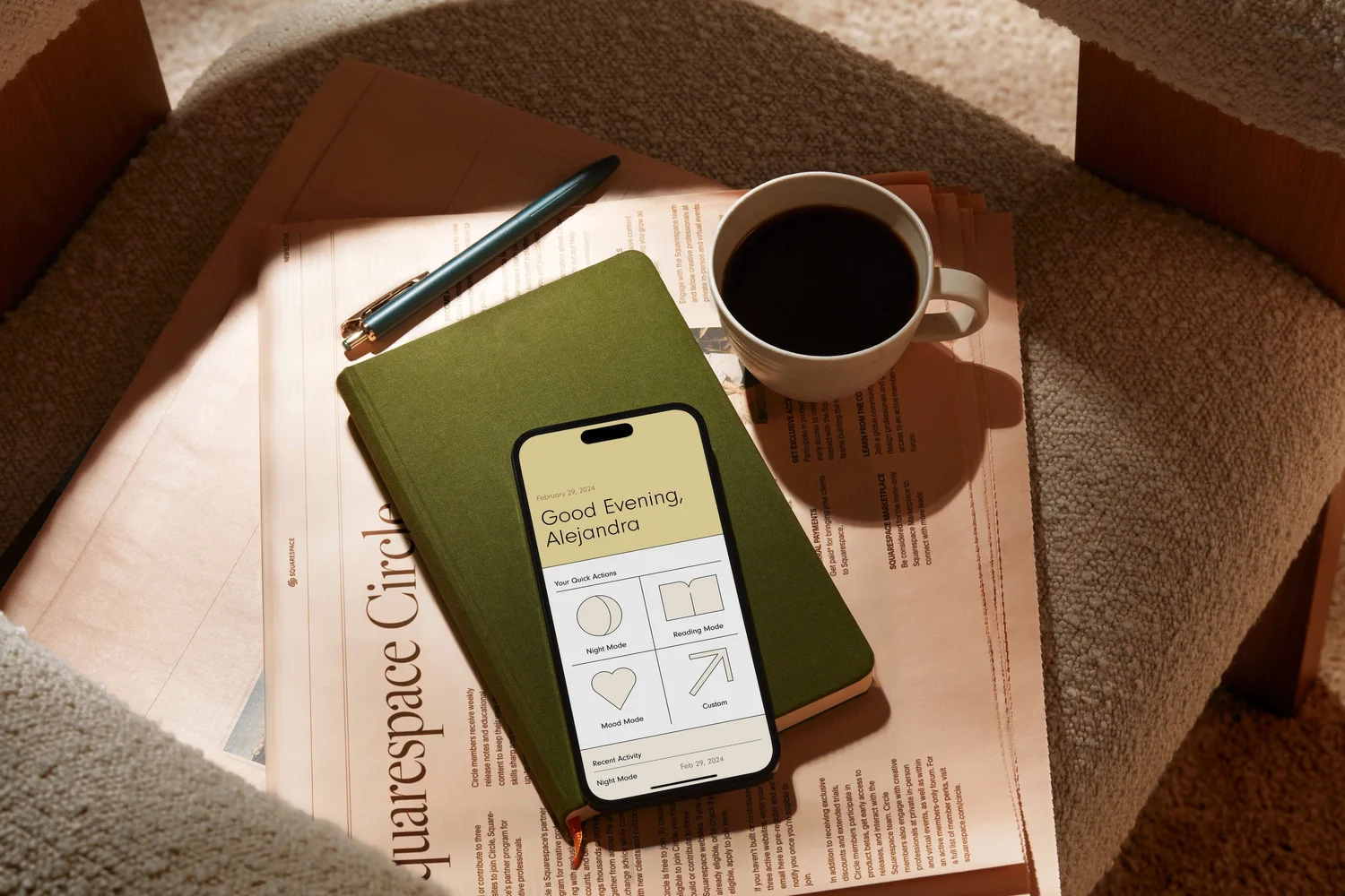 Coffee cup, pen and a notebook with a phone on a desk